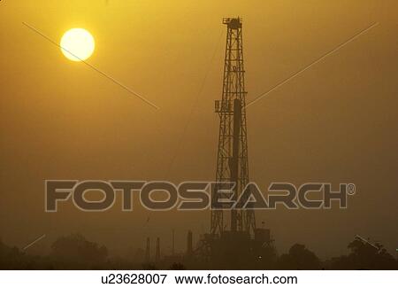 Stock Photo - Onshore Oil Drilling Rig Silhouette and Sun. Fotosearch