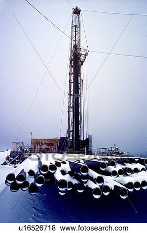 Stock Photo - Onshore Oil Drilling Rig with Drill Pipe Stacked in Foreground Covered in Snow. Fotosearch