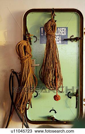 Stock Image - Steel Door on Cargo Ship with Monkey Fist Knot on Rope. Fotosearch