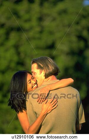 Stock Photograph - park, couple, gate, golden, embrace, love. Fotosearch