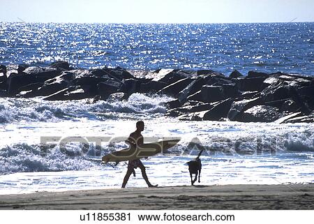 Stock Image - male, runs, surfboard, carrying, young. Fotosearch