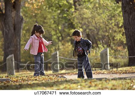 Stock Image - scenic, looking, leaves, autumn, down, siblings. Fotosearch
