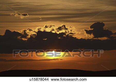 Picture - clouds, sun, behind, out, coming, setting. Fotosearch