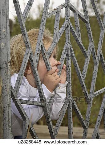 Stock Photography - fence, girl, behind, little, posing, pretty. Fotosearch