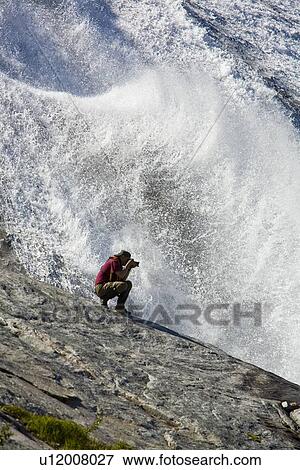 A photographer at a snow melt waterfall in Nordfjord, an arm of the larger Melfjord - situated just above the Arctic Circle - in northern Norway, Barents Sea. View Large Photo Image Stock Photo - A photographer at a snow melt waterfall in Nordfjord, an arm of the larger Melfjord - situated just above the Arctic Circle - in northern Norway, Barents Sea.. Fotosearch