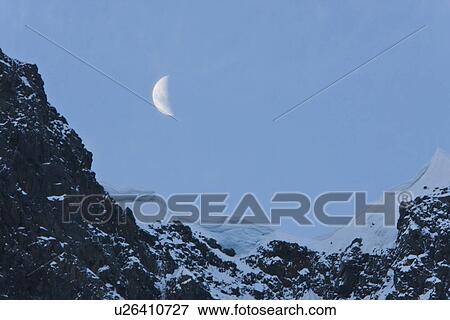 A waxing moon showing over snow covered cliffs in the Lemaire Channel on the west side of the Antarctic peninsula. View Large Photo Image Stock Photo - A waxing moon showing over snow covered cliffs in the Lemaire Channel on the west side of the Antarctic peninsula.. Fotosearch