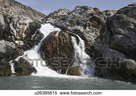 Stock Photography - Glacier melt water forms a small waterfall in Tracy Arm in southeast Alaska, USA.. Fotosearch