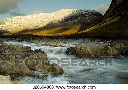 Stock Photo - River Etive flowing through Glen Etive in winter with moon on horizon. Slow shutter speed. Argyll Scotland, UK. Fotosearch