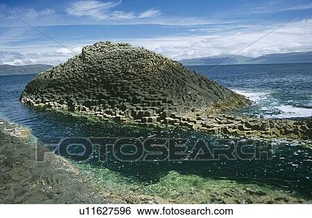 Stock Photograph - The 'Herdsman', Staffa. This basalt column rock formation sits close to the one safe landing spot for larger boats on Staffa. Hebrides, Scotland. Fotosearch