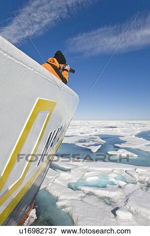 A photographer on the bow of the expedition travel ship National Geographic Endeavour photographing the ice leads in the Barents Sea, Norway. View Large Photo Image Stock Photo - A photographer on the bow of the expedition travel ship National Geographic Endeavour photographing the ice leads in the Barents Sea, Norway.. Fotosearch