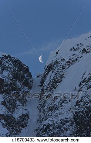 Stock Image - A quarter moon setting over the scenic Lemaire Channel on the west side of the Antarctic peninsula in Antarctica.. Fotosearch