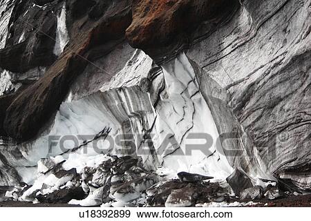 Stock Photo - Close up views of glacial ice and ash after the 1969 eruption on Deception Island in Antarctica. Note how the ash is suspended within the ice itself. Though it looks like marble. the dark striations are actually volcanic ash in the ice.. Fotosearch