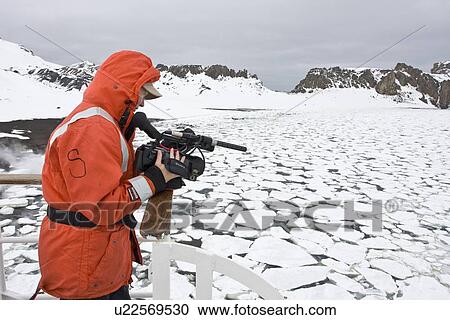 Stock Image - Crew videographer Anika of the Lindblad Expedition ship National Geographic Endeavour at work in the crow's nest on Deception Island in Antarctica.. Fotosearch