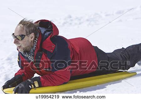 Lindblad Expeditions guest riding a snow board down a hill in Antarctica as part of expedition travel. NO MODEL RELEASES FOR THIS IMAGE. View Large Photo Image Stock Photo - Lindblad Expeditions guest riding a snow board down a hill in Antarctica as part of expedition travel. NO MODEL RELEASES FOR THIS IMAGE.. Fotosearch