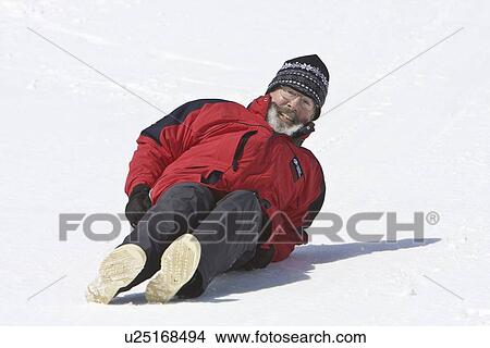 Picture - Lindblad Expeditions guest sliding down a hill on their snow pants in Antarctica as part of expedition travel. NO MODEL RELEASES FOR THIS IMAGE.. Fotosearch