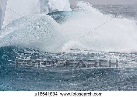 Picture - Massive waves breaking on iceberg detail in and around the Antarctic Peninsula during the summer months. More icebergs are being created as global warming is causing the breakup of major ice shelves and glaciers.. Fotosearch