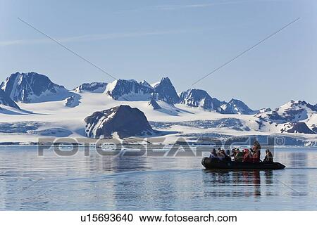 Stock Image - Zodiac cruisers get a view of the tidewater glacier in Isbukta (Ice Bay) on the western side of Spitsbergen Island in the Svalbard Archipelago, Barents Sea, Norway. This glacier is receeding, probably due to global warming.. Fotosearch