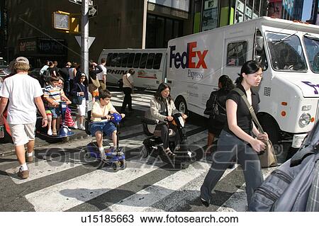 Stock Image - A woman and child with disabilities on a crossing a busy street in New York City.. Fotosearch