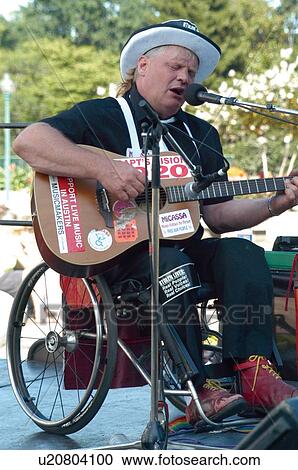 Stock Image - Man in a wheelchair (with a disability) playing a guitar at the ADAPT March on Washington to advocate for the civil rights of people with disabilities.. Fotosearch