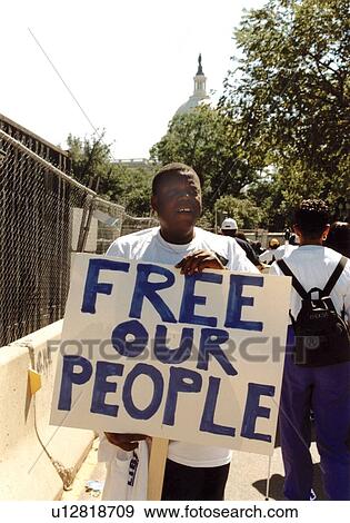Stock Photo - Man with a disability holding a sign Free Our People on his way to the O. S. Capitol.. Fotosearch