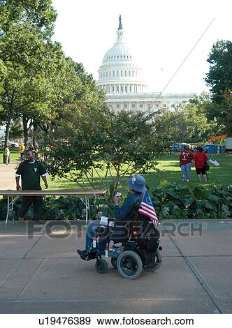 Stock Photo - Man with a disability utilizing motorized/power wheelchair for mobility looking at the Nation's Capitol while participating in the ADAPT March on Washington advocacy event.. Fotosearch
