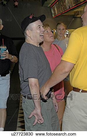 Stock Image - People with disabilities laughing and conversing as they prepare to order refreshments for their movie.. Fotosearch