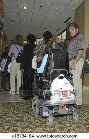 Person with a disability, using a scooter for mobility, waiting in line at a conference. View Large Photo Image Picture - Person with a disability, using a scooter for mobility, waiting in line at a conference.. Fotosearch