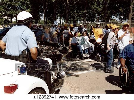 Policeman monitoring and assisting at a national disability civil rights event with people with disabilities marching to the O. S. Capitol. View Large Photo Image Stock Image - Policeman monitoring and assisting at a national disability civil rights event with people with disabilities marching to the O. S. Capitol.. Fotosearch