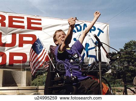 Powerful image of a young man with a disability who utilizes a wheelchair for mobility speaking to a crowd of people with disabilities at the ADAPT March on Washington Disability Advocacy event. View Large Photo Image Stock Photo - Powerful image of a young man with a disability who utilizes a wheelchair for mobility speaking to a crowd of people with disabilities at the ADAPT March on Washington Disability Advocacy event.. Fotosearch