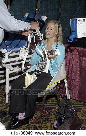 Stock Photo - Woman sitting in and testing the remote controls for bathing lift and transfer equipment while a man demonstrates the use of the equipment.. Fotosearch