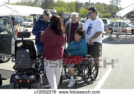 Stock Photograph - Woman (wheelchair user) and small group visit at a community fair. Fotosearch