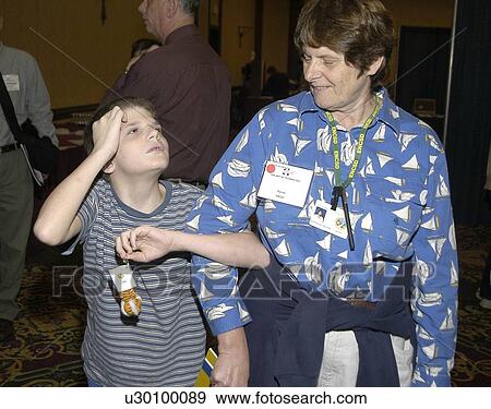 Young boy with visual impairment/blindness receiving assistance from sighted person at conference. View Large Photo Image Stock Photo - Young boy with visual impairment/blindness receiving assistance from sighted person at conference.. Fotosearch