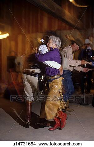 Couple dressed in chaps and cowboy boots dances on the floor of a Western Tavern View Large Photo Image Picture - Couple dressed in chaps and cowboy boots dances on the floor of a Western Tavern. Fotosearch