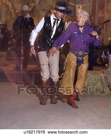 Couple dressed in chaps and cowboy boots dances on the floor of a Western Tavern View Large Photo Image Stock Photograph - Couple dressed in chaps and cowboy boots dances on the floor of a Western Tavern. Fotosearch