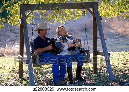 couple sitting outdoors on a swing with their pets View Large Photo Image Stock Photo - couple sitting outdoors on a swing with their pets. Fotosearch