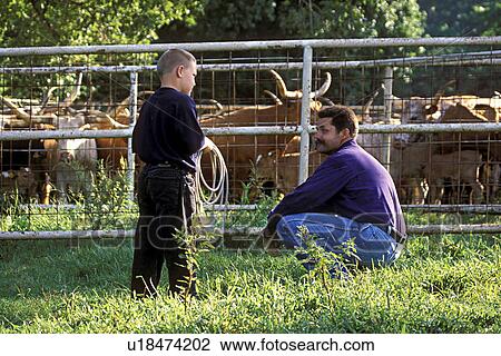 Man and boy, with lariat in hand, converse outside cattle corral. View Large Photo Image Stock Image - Man and boy, with lariat in hand, converse outside cattle corral.. Fotosearch