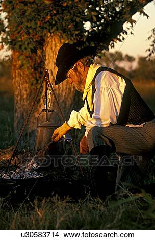 man cooking over a fire in the morning View Large Photo Image Picture - man cooking over a fire in the morning. Fotosearch
