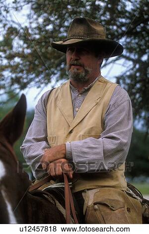 Stock Photo - man in authentic western clothes sitting on his horse. Fotosearch