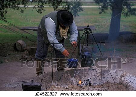 man moving a pot off of the campfire View Large Photo Image Stock Photo - man moving a pot off of the campfire. Fotosearch