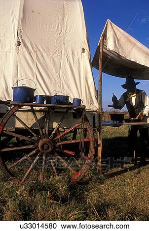 man preparing to use pots and pans sitting on a wagon wheel View Large Photo Image Stock Image - man preparing to use pots and pans sitting on a wagon wheel. Fotosearch