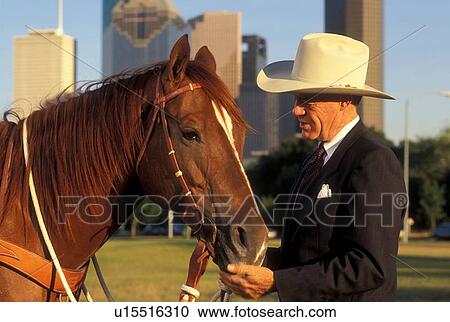 Stock Image - man standing with a horse in front of the downtown Houston skyline. Fotosearch