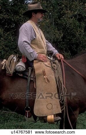 Stock Image - profile of a man in western clothes sitting on his horse. Fotosearch
