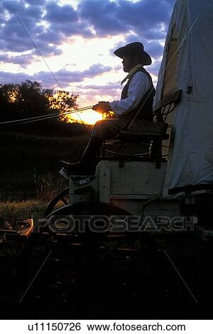 side view of a man sitting on a western wagon at sunset View Large Photo Image Stock Photograph - side view of a man sitting on a western wagon at sunset. Fotosearch