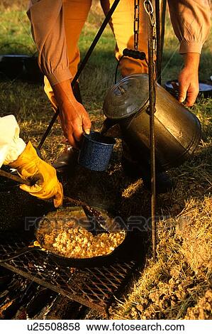 two people preparing breakfast on a campfire View Large Photo Image Stock Photo - two people preparing breakfast on a campfire. Fotosearch