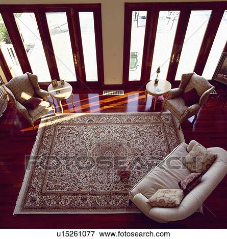 Aerial view of modern livingroom with cream sofa and large patterned carpet on polished wood floor in front of patio doors View Large Photo Image Stock Photo - Aerial view of modern livingroom with cream sofa and large patterned carpet on polished wood floor in front of patio doors. Fotosearch