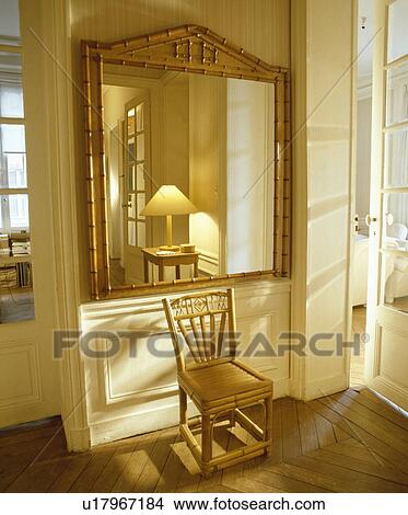 Antique bamboo mirror above bamboo chair in white hall with reflection of lamp in mirror View Large Photo Image Picture - Antique bamboo mirror above bamboo chair in white hall with reflection of lamp in mirror. Fotosearch