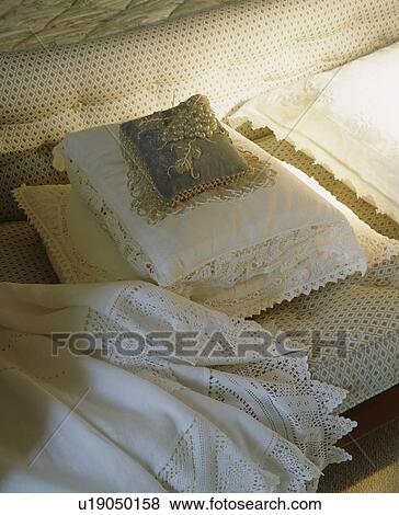 Antique beaded cushion on lace-trimmed white cushions and lace-trimmed sheet on upholstered bedroom stool View Large Photo Image Stock Photo - Antique beaded cushion on lace-trimmed white cushions and lace-trimmed sheet on upholstered bedroom stool. Fotosearch