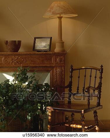 Stock Image - Antique chair and lighted lamp in traditional living room. Fotosearch