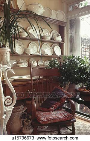 Antique chair in front of dresser with white crockery in corner of dining room with houseplant on low table View Large Photo Image Stock Image - Antique chair in front of dresser with white crockery in corner of dining room with houseplant on low table. Fotosearch