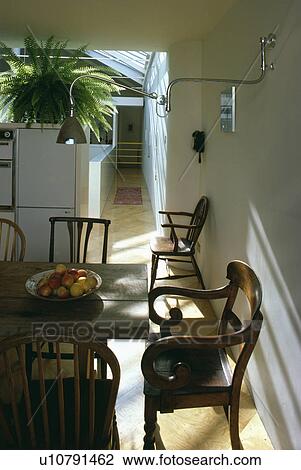 Stock Image - Antique chairs in modern white sixties dining room. Fotosearch